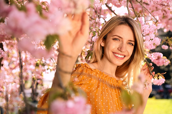 A woman dressed for spring standing under a blossom tree